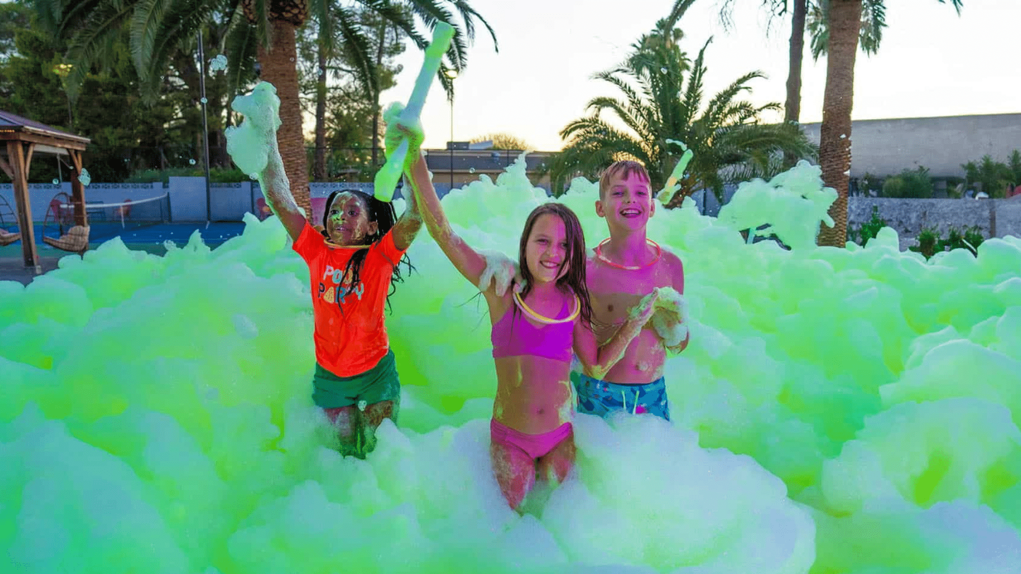 Kids playing in a foam filled backyard on summer day